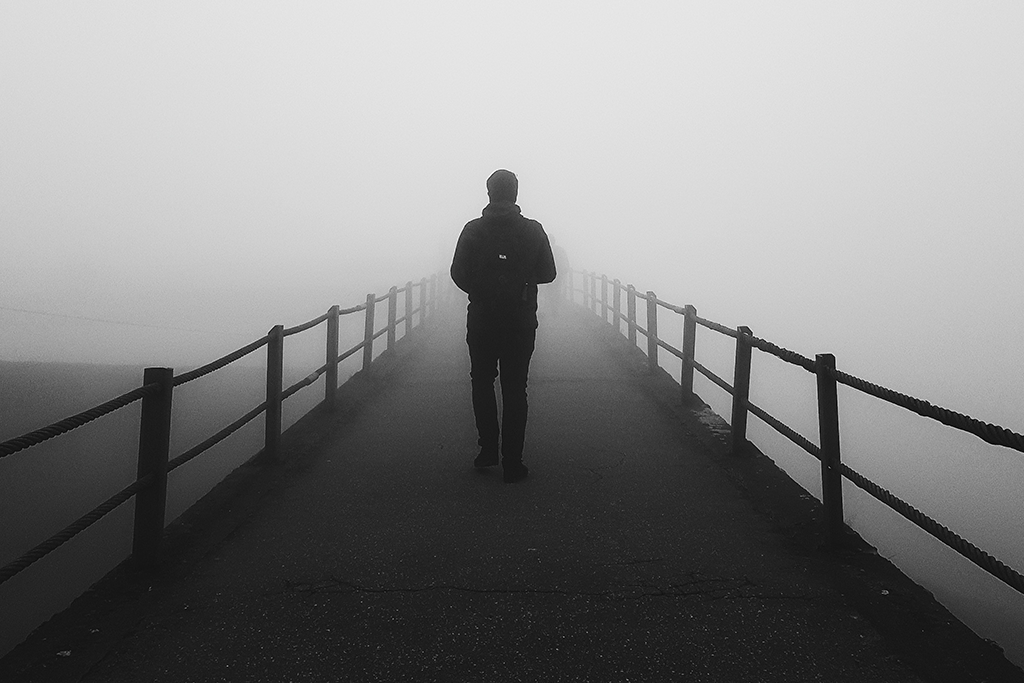 Cognitive Performance, Man walking bridge in the fog unsure of where to go, black and white photo